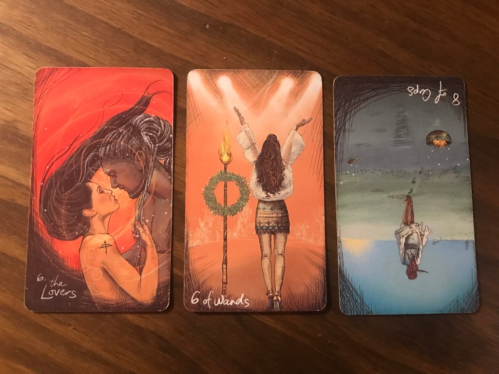 Three tarot cards: the Lovers, 6 of wands, and 8 of cups reversed.